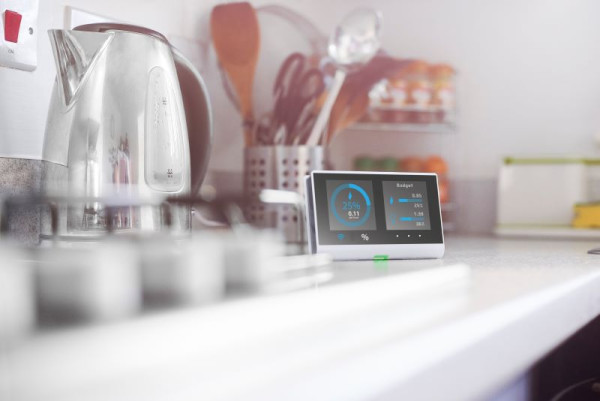 Kitchen bench with a stainless steel kettle, a smart device that measures energy and cooking utensils